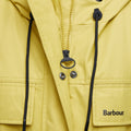 Close-up of a yellow Evie Showerproof Parka by Barbour, featuring a zipper, snap buttons, drawstrings, and the Barbour logo on a front pocket. The weather-protective parka has an adjustable hood for added functionality.