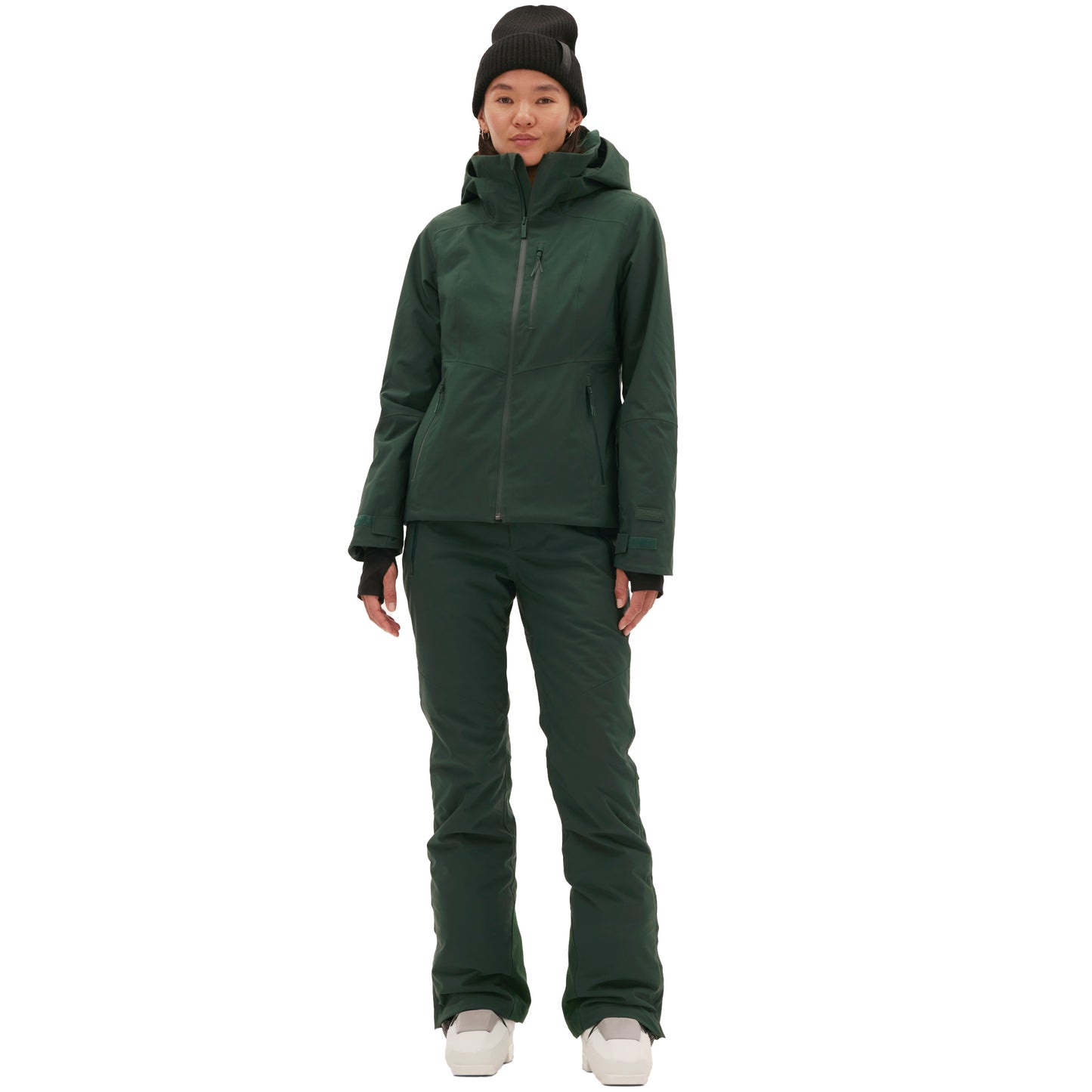 A woman wearing a Halfdays Lawrence Jacket with matching pants and a black beanie stands confidently against a plain white background, complemented by her white shoes.