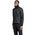 A person in a fitted black Layton Men's Tactical Hybrid Sweater by Nobis with Primaloft Gold Insulation and dark jeans stands against a white background, looking to the side.