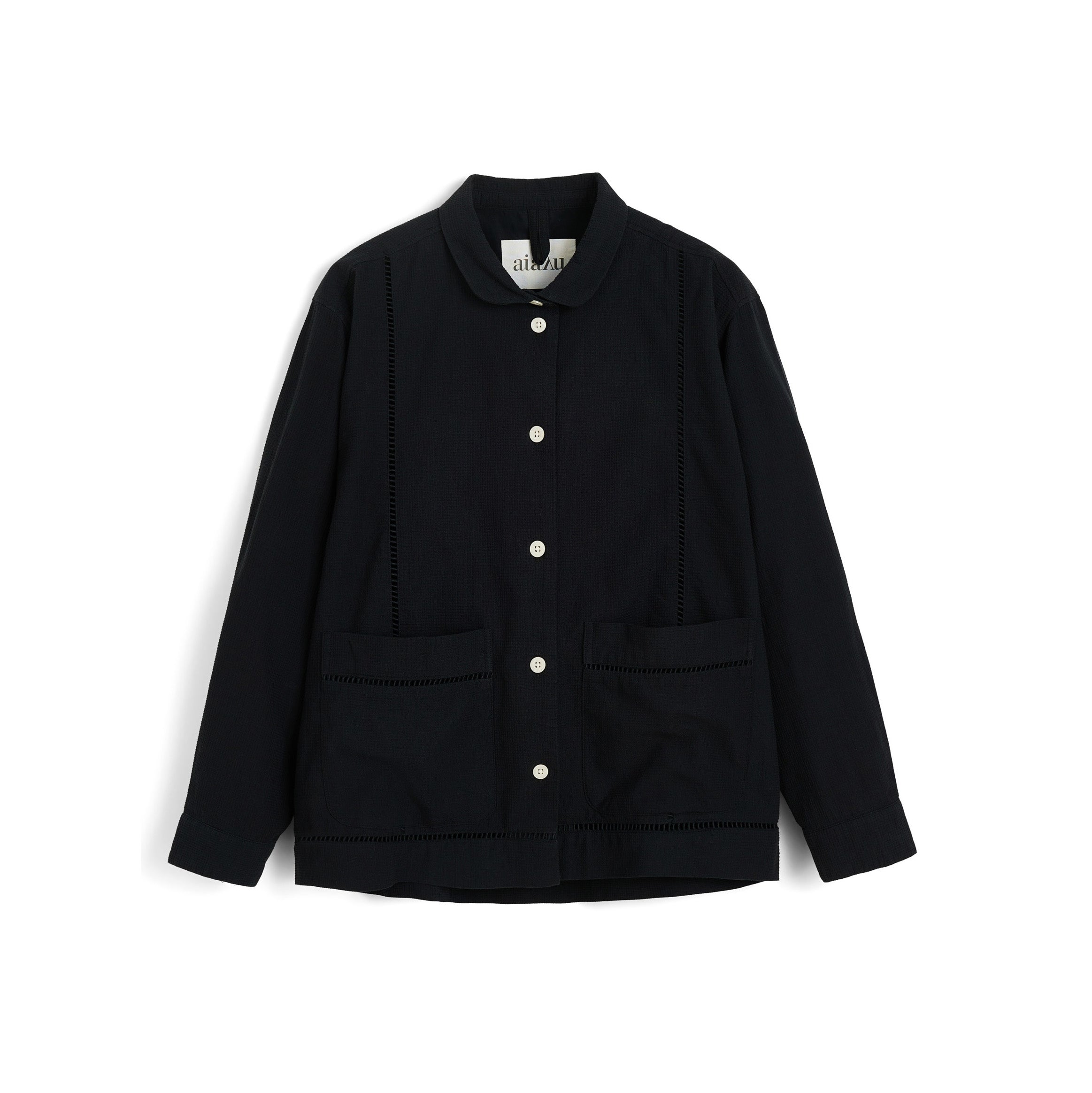 The Aiayu Lucie Chetna Cotton Shirt Waffle is a black organic cotton button-up with white buttons, two front patch pockets, and a collar, shown against a white background.