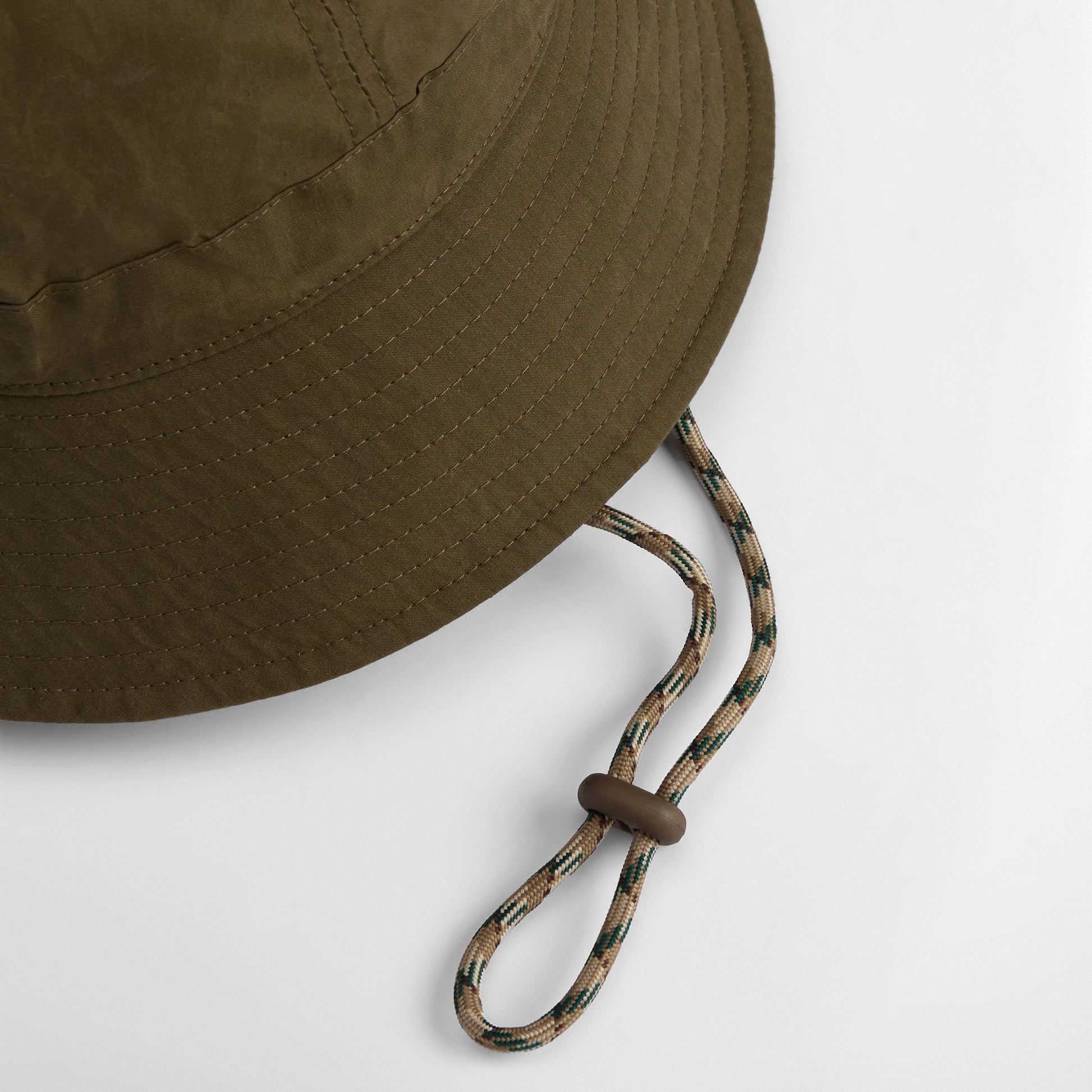 The Barbour Transport 6 Panel Bucket Hat in olive green features visible stitching and an adjustable chin strap with toggle, shown against a white background.