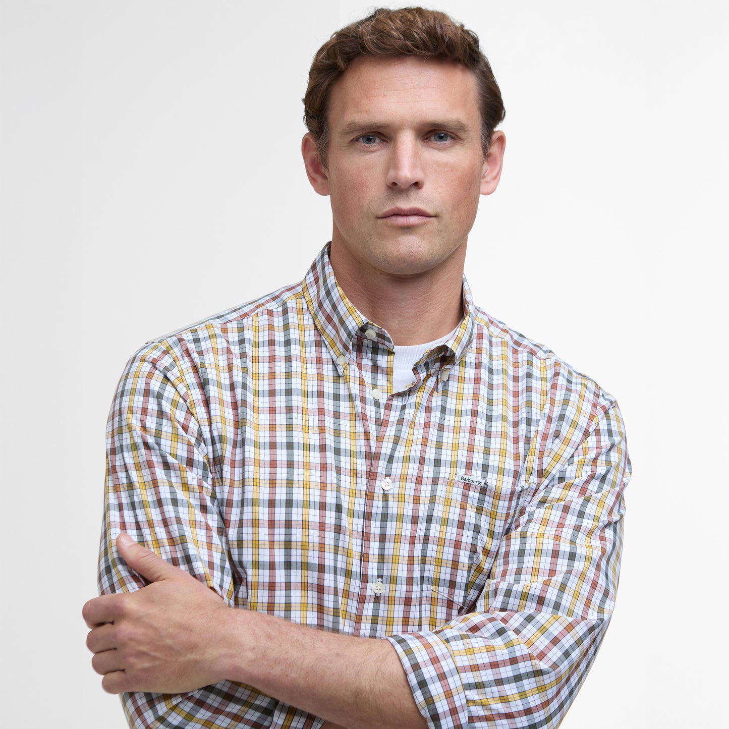 A person wearing the Barbour Hallhill Performance Shirt with a classic check design stands with arms crossed, looking forward against a plain background.