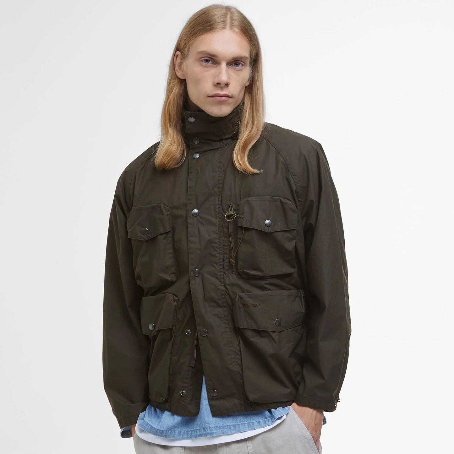 A person with long blonde hair wears a Barbour Westmorland Showerproof Jacket, famed for its functionality and multiple pockets, against a plain white background.