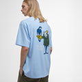 Wearing Barbour's Newclyde Graphic T-Shirt, an oversized, archive-inspired light blue tee featuring a back graphic of a cartoon character with a bird, standing against a plain background.