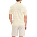 A man stands with his back to the camera, wearing Dockers Men's Sweater Polo—a short-sleeve light beige BCI Cotton sweater with subtle horizontal stripes—and light-colored shorts.
