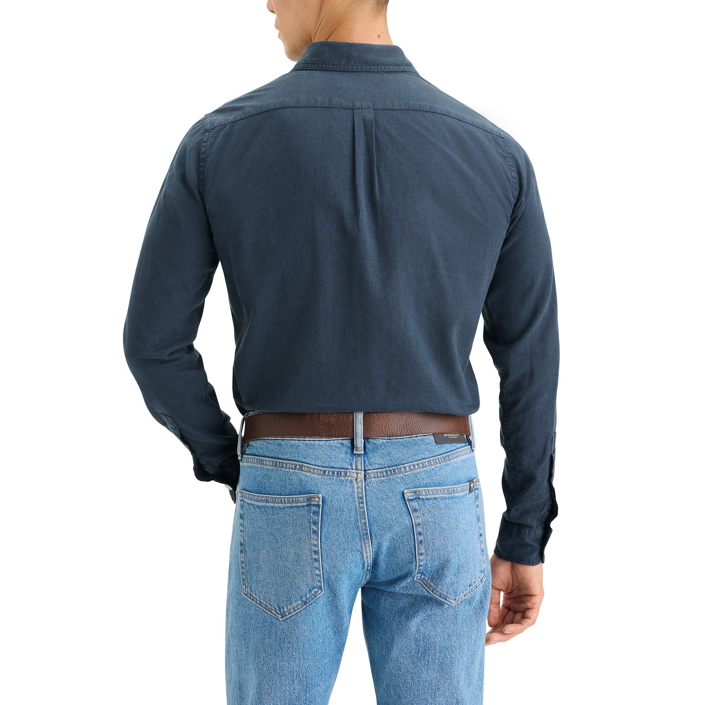 A person in Dockers' Men's Original Shirt, LS is seen from behind. The dark blue button-up shirt is tucked into blue jeans, enhanced by a brown belt for a clean and comfortable look.