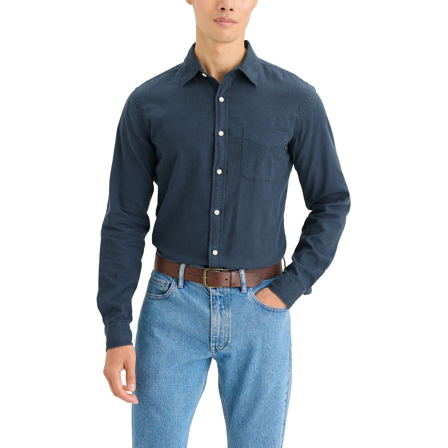 A person sporting a clean-cut look in a Dockers Men's Original Shirt, LS paired with light blue jeans, one hand casually in the pocket, and a brown belt visible.