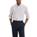 A man wearing the Dockers Men's Signature Shirt, LS—a white button-up with thin black stripes—and dark navy dress pants, stands with his hands in his pockets.