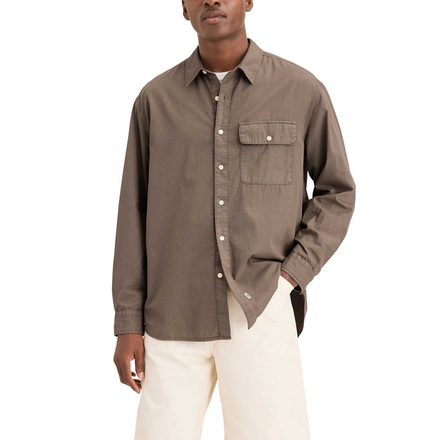 Someone stands against a white background wearing the Genderless 86 1-Pocket Shirt, LS in brown cotton ripstop with cream-colored pants.