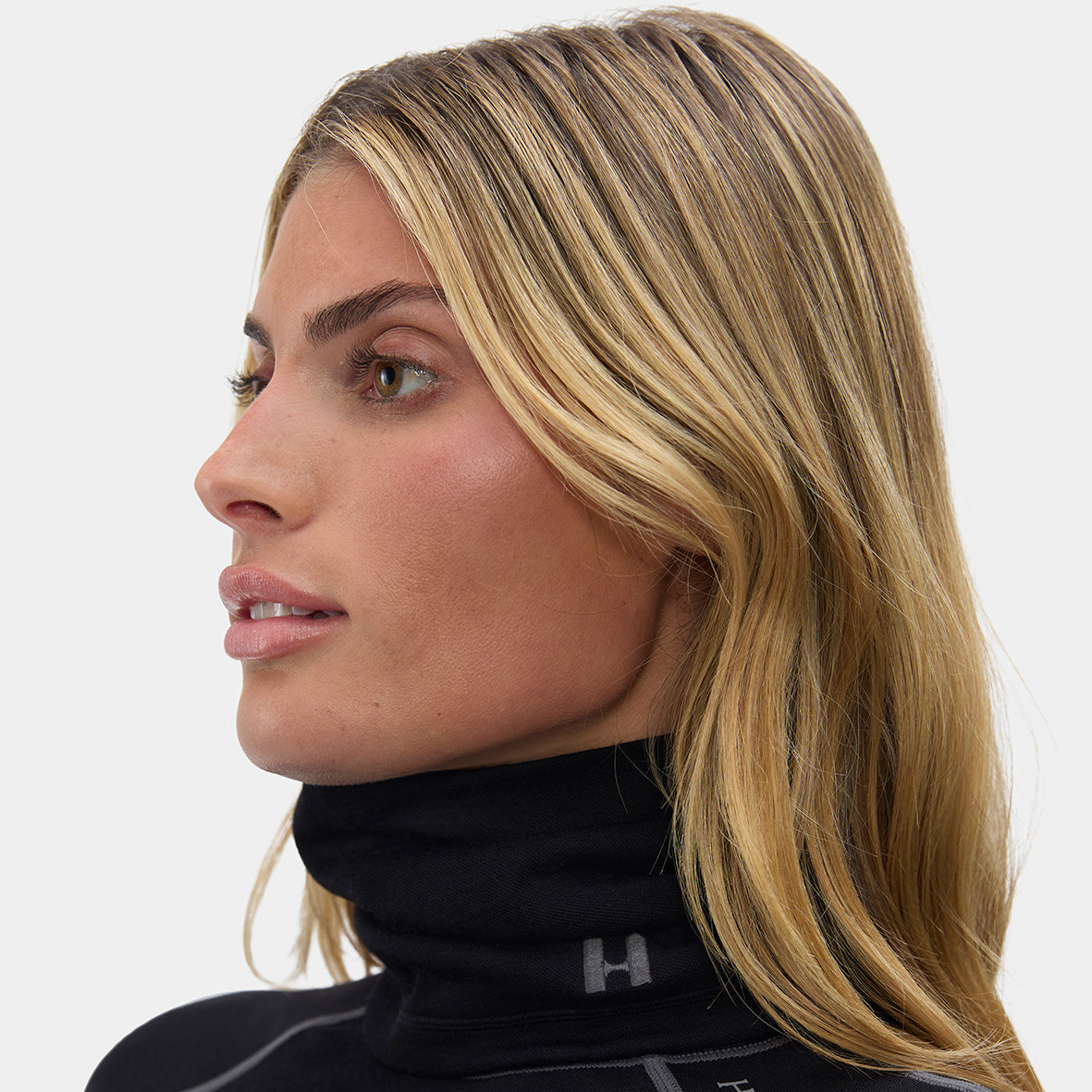 Woman wearing a black high-neck gaiter with a brand logo "H" on a white background
