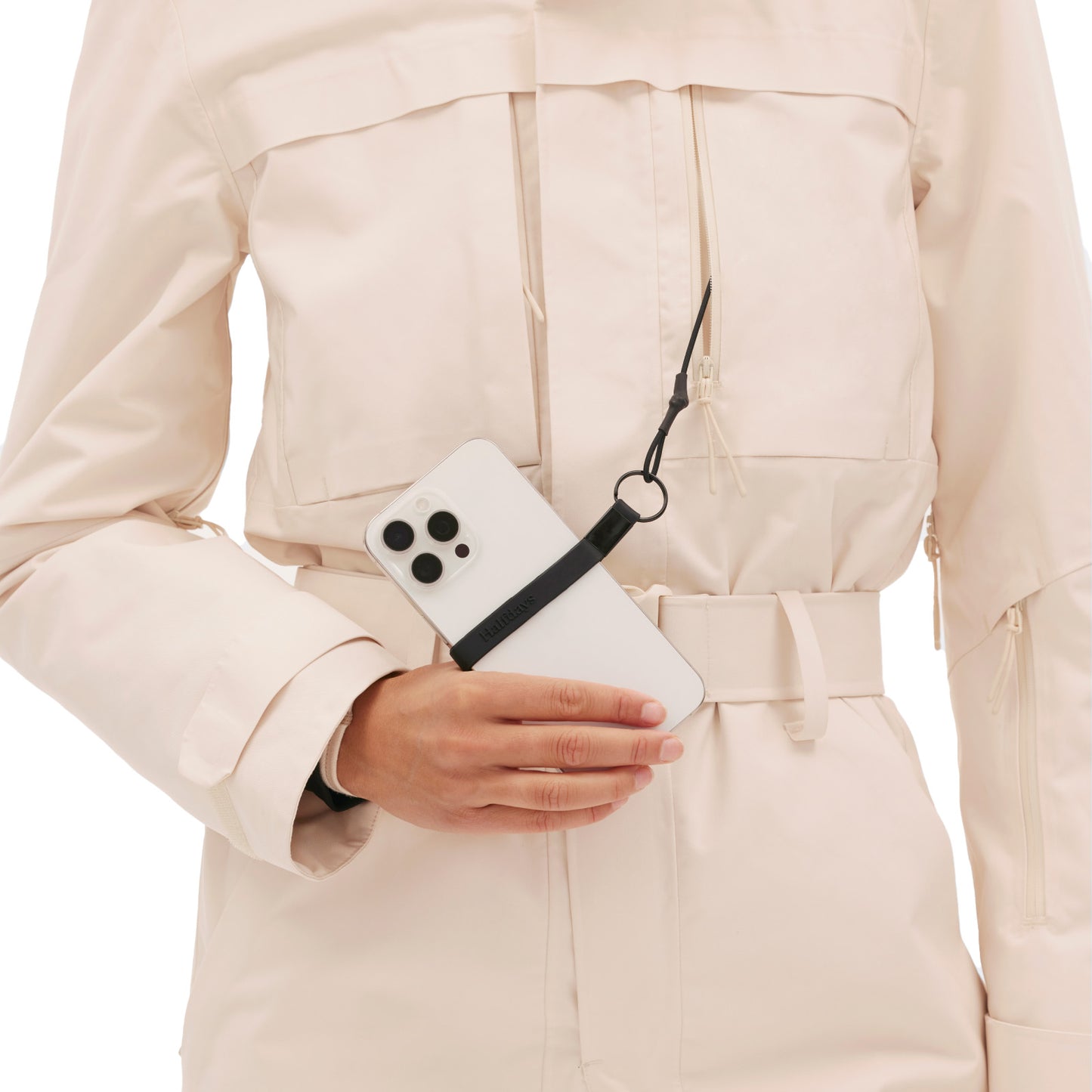 A person in a Halfdays vintage racing-style Murphy Ski Suit holds a smartphone with a black strap attached.