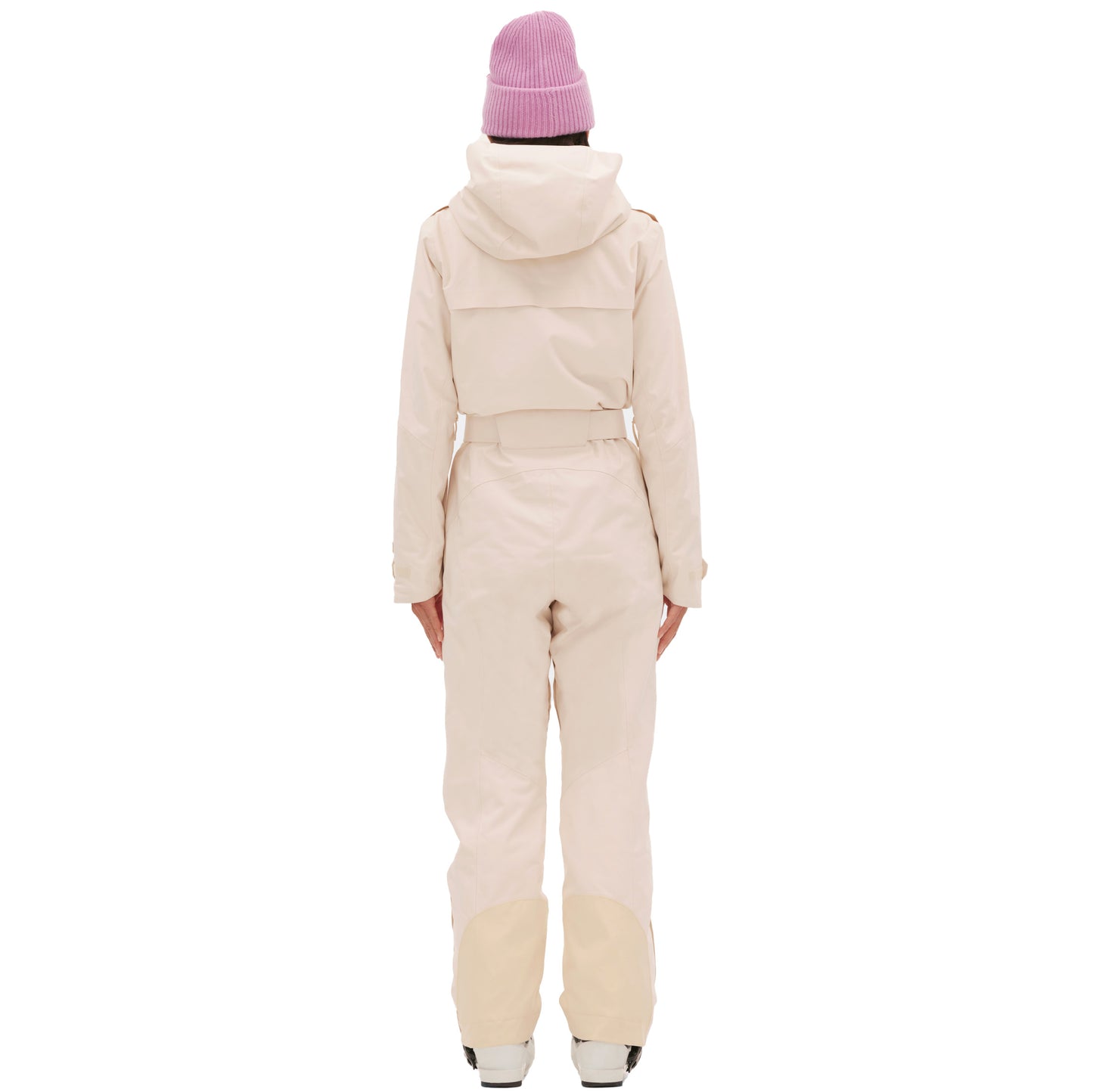 A person in a cream-colored Murphy Ski Suit by Halfdays and a pink beanie, stands with their back to the camera against a white background.