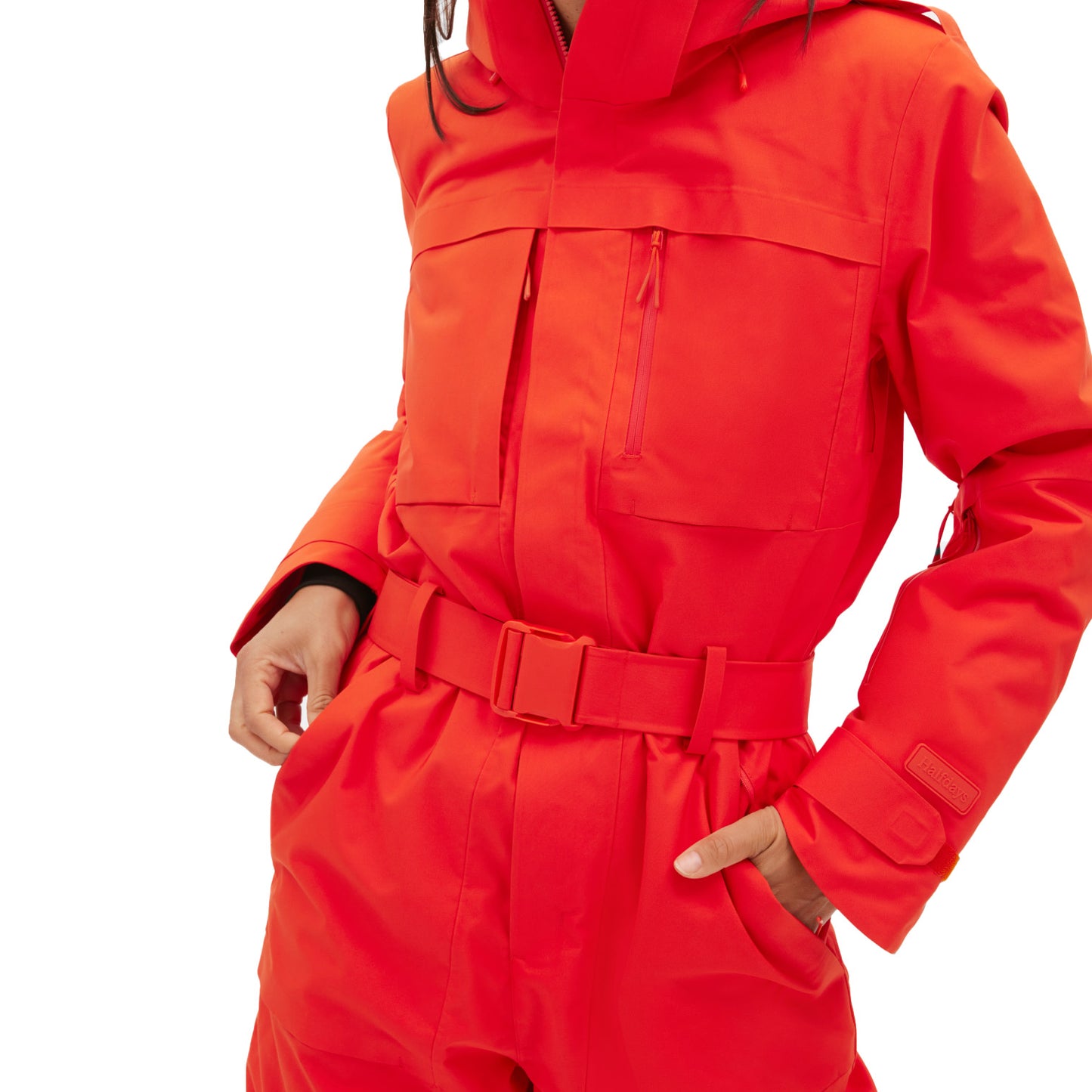 A person wearing a red Halfdays Murphy Ski Suit in a vintage racing style, with hands in pockets and visible torso, displaying part of the hood.