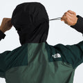 Person adjusts the hood of their black and green M Signal 2.5L DryVent jacket from The North Face, pulling on the drawstring at the back.