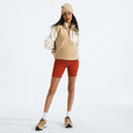A person wears a beige W Yumiori 1/4 Zip fleece pullover by The North Face, paired with red shorts, a matching beanie, and hiking shoes. They pose confidently against a white background, showcasing eco-friendly fashion choices.