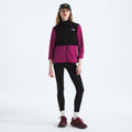 A person in a black and magenta W Glacier Fleece Jacket by The North Face, made from recycled fabric, pairs it with black leggings, maroon shoes, and a green cap against a white background.