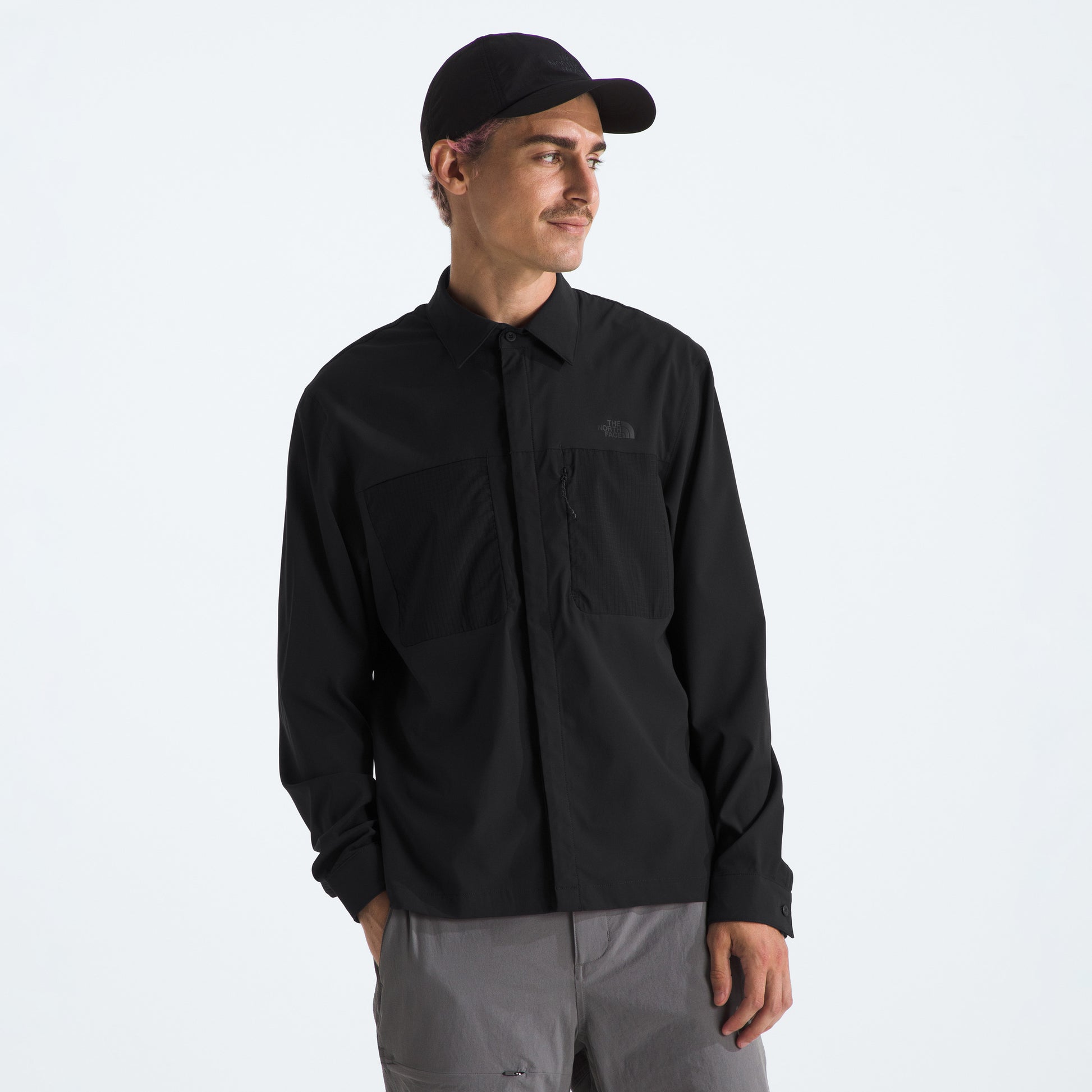 A person in a black M L/S LIGHTRANGE Shirt by The North Face stands against a plain background, looking sideways. This moisture-managing shirt ensures on-trail comfort, perfect for any adventure.