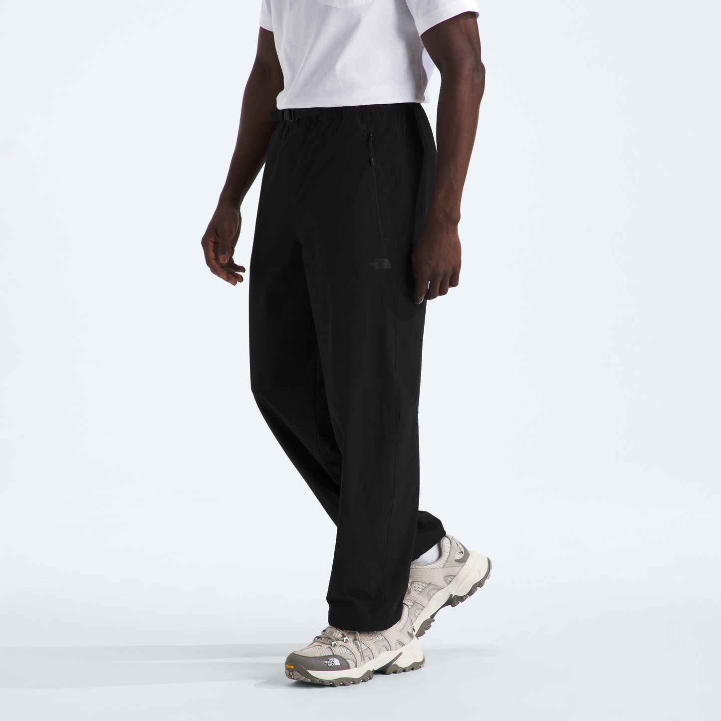 Someone in The North Face M North Dome Wind Pant with a white t-shirt and white sneakers, standing against a plain background.