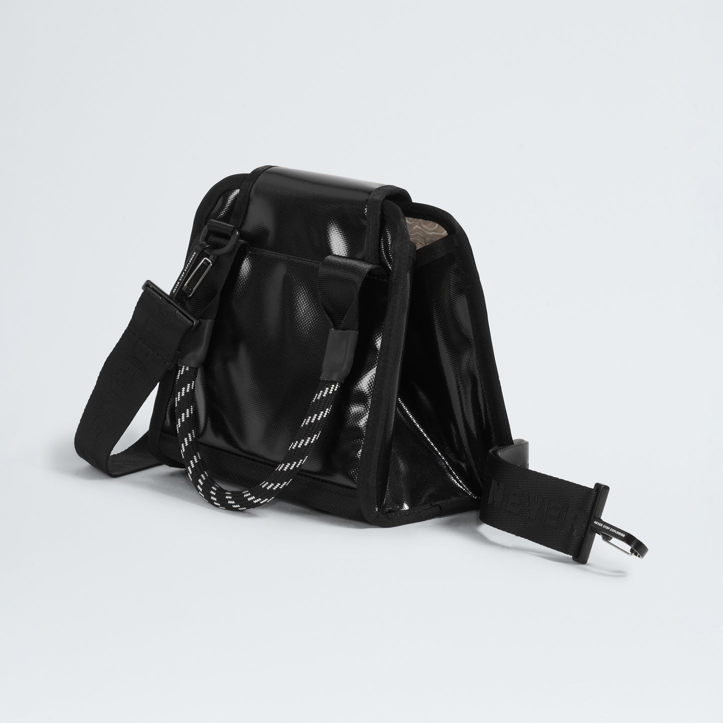 The North Face Base Camp Mini Tote, made from recycled fabric, showcases a glossy black look with a striped handle. Its stylish design features a shoulder strap, top flap opening, and internal organization to keep essentials secure.