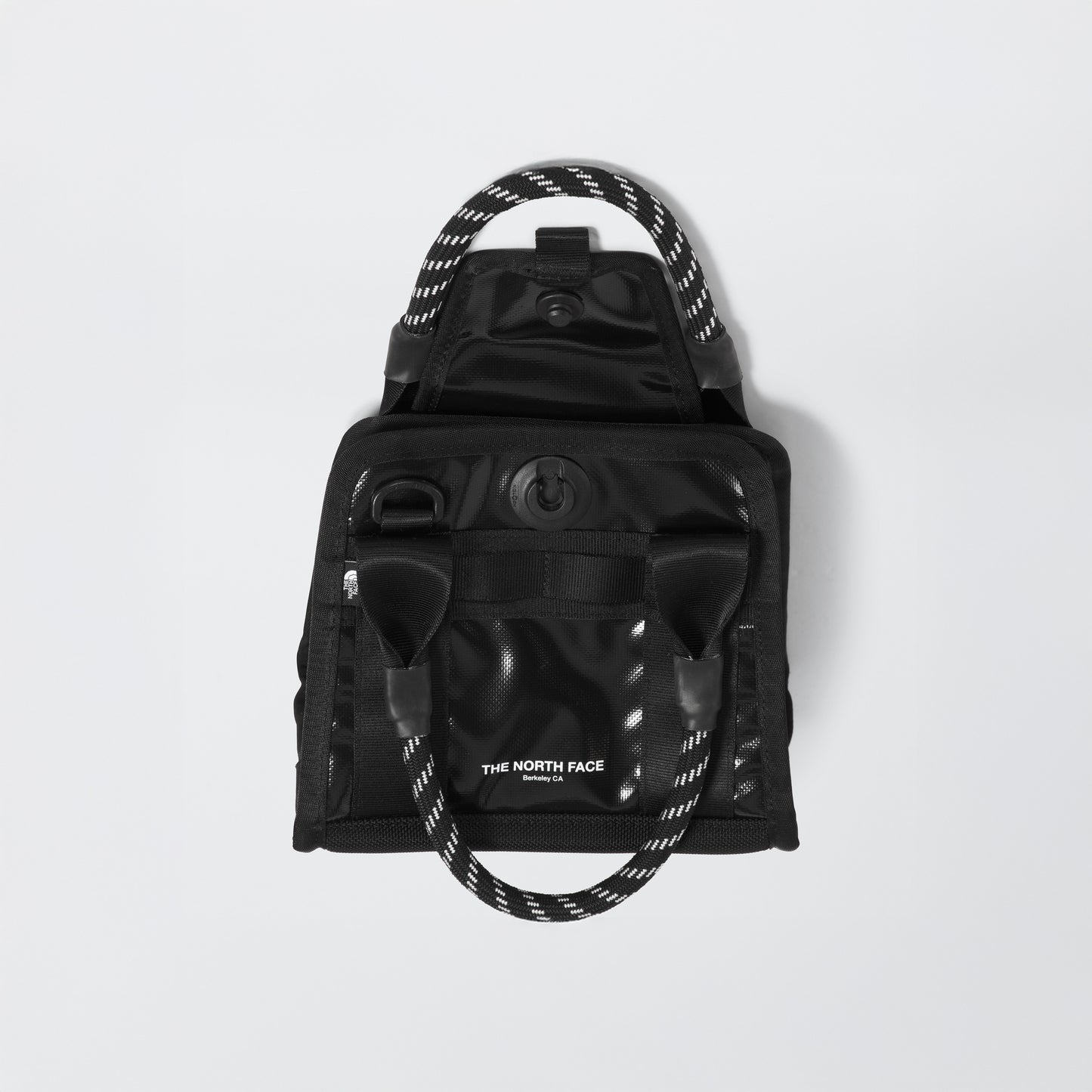 A Base Camp Mini Tote by The North Face, featuring a black and white design with a rope handle and made from recycled fabric, is set against a plain white background.