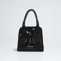 The Base Camp Mini Tote by The North Face, made from recycled fabric, features a black glossy finish, patterned handles, and the iconic logo on a plain white background.