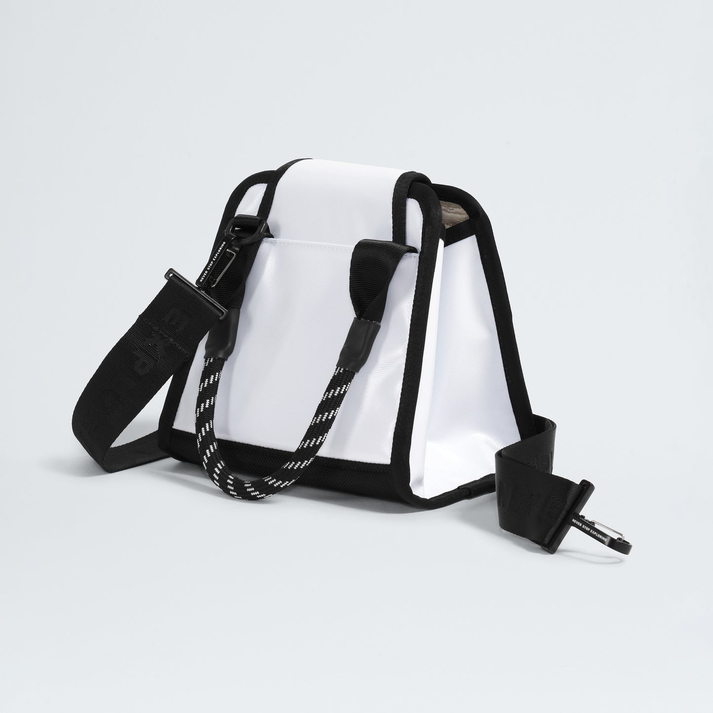 The North Face's Base Camp Mini Tote, made from recycled fabric, features a white and black trapezoidal design with internal organization, a detachable shoulder strap, and a striped handle against a plain background.