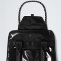The North Face Base Camp Tote Bag is shown in black with a glossy finish, flap and snap closure, two front straps, braided rope handles, and smart internal organization—offering durable style against a pale background.