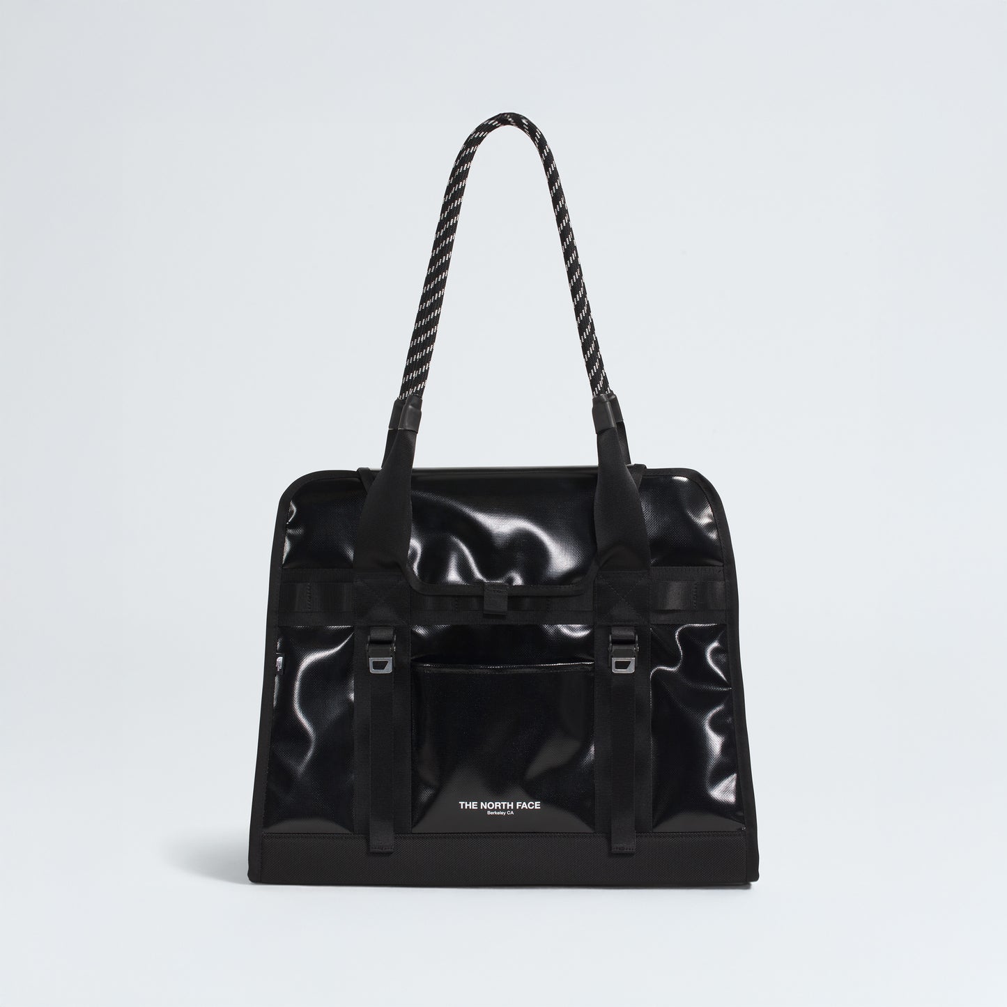The North Face Base Camp Tote Bag is a black, glossy tote with rope handles, a front pocket, and the logo on the lower front. It features durable construction and internal organization for your essentials.
