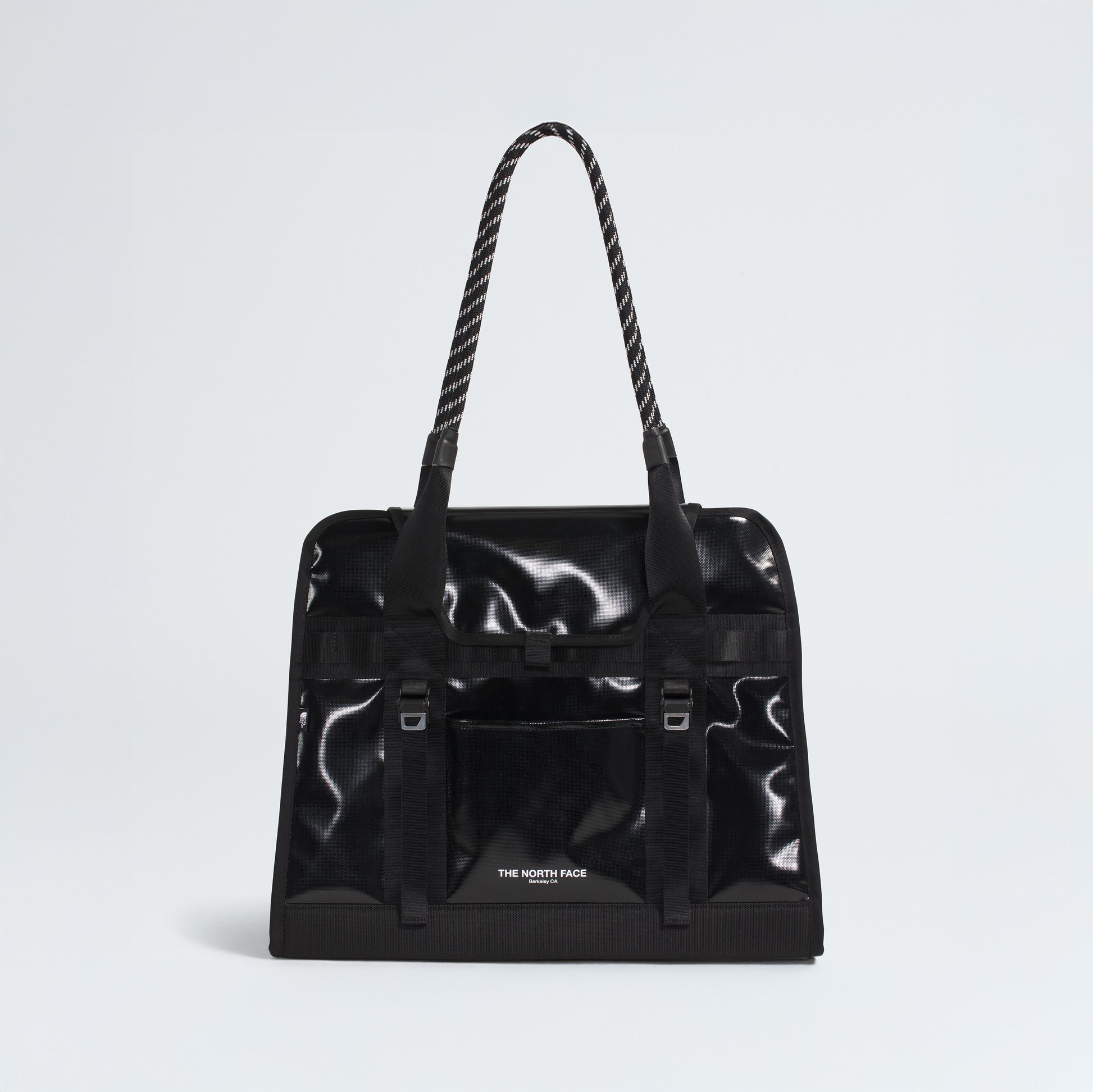 The North Face Base Camp Tote Bag is a black, glossy tote with rope handles, a front pocket, and the logo on the lower front. It features durable construction and internal organization for your essentials.