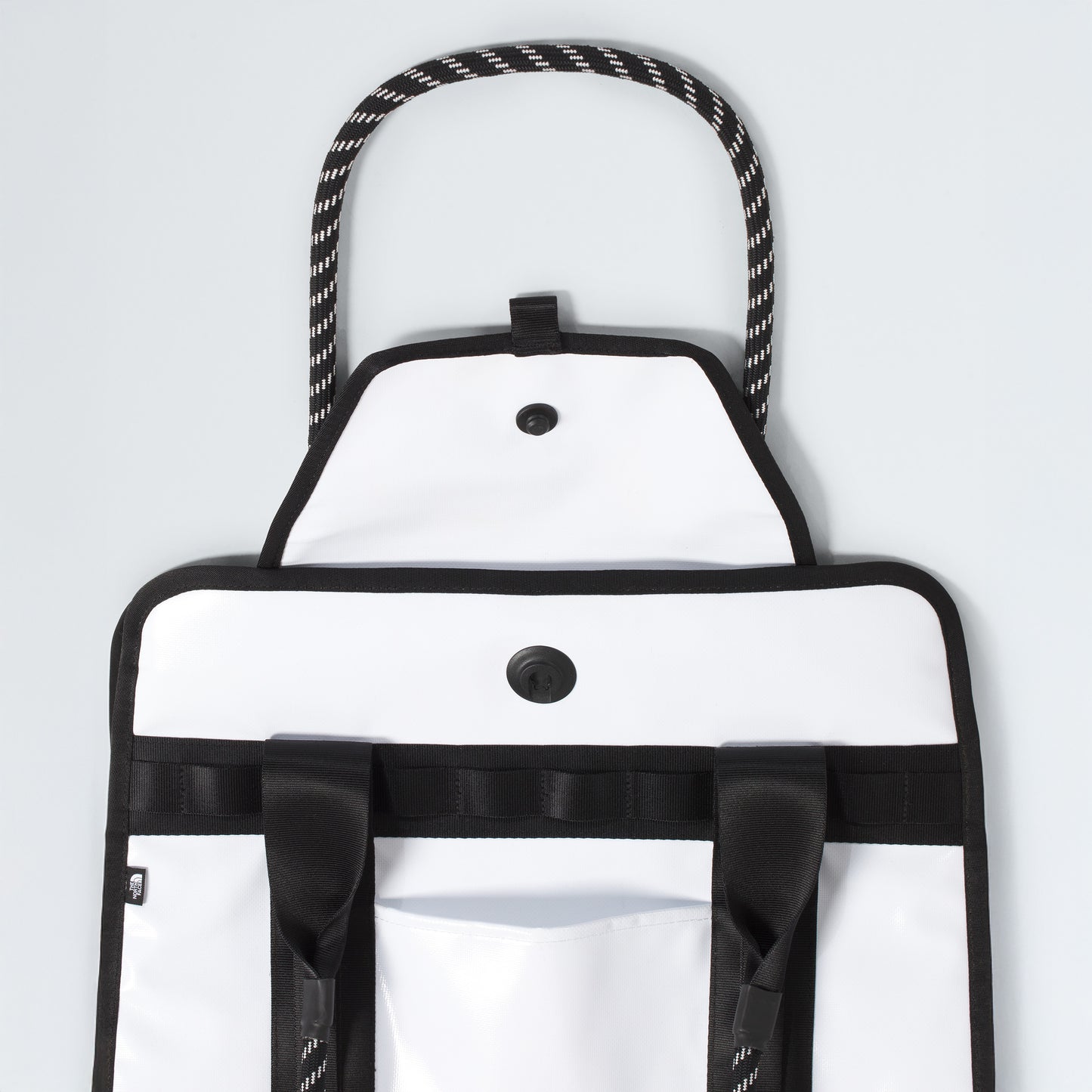 The North Face Base Camp Tote Bag features black trim, rope handles, button closures, durable construction, black straps, a front pocket, and smart internal organization—all shown against a plain background.