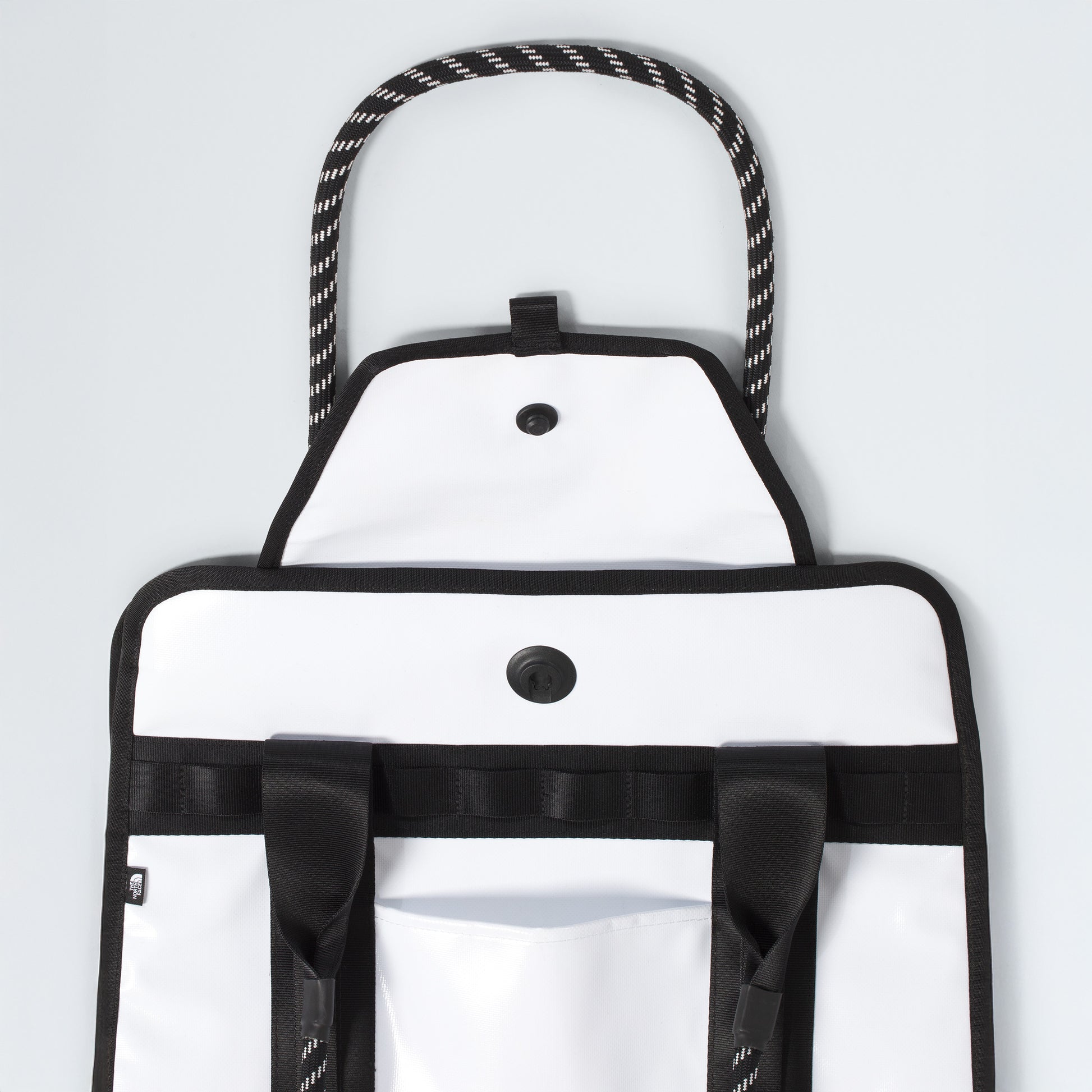 The North Face Base Camp Tote Bag features black trim, rope handles, button closures, durable construction, black straps, a front pocket, and smart internal organization—all shown against a plain background.