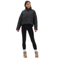 A person wearing a Halfdays Nellie Packable Puffer Jacket, black leggings, and tan boots stands with hands on hips against a white background, ready for outdoor adventure.