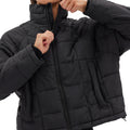 A person zips up the black Nellie Packable Puffer Jacket by Halfdays, ready for an outdoor adventure.