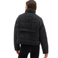 Wearing the Nellie Packable Puffer Jacket by Halfdays and black pants, a person faces away from the camera, perfectly attired for an outdoor adventure.