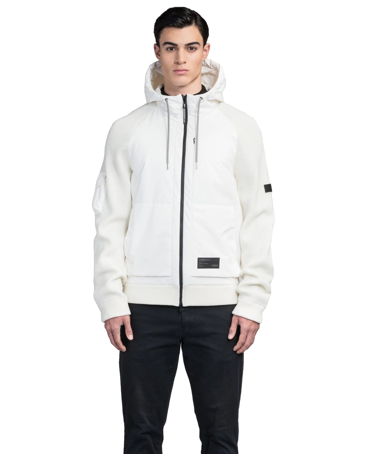 A person wearing the Hedge Men's Performance Hoodie by Nobis, a luxurious zip-up with a hood and black drawstrings made from merino wool for added warmth, paired with dark pants against a plain white background.