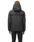 A person stands against a white background wearing a Nobis Oliver Men's Reversible Puffer Jacket, seamlessly transitioning from day to night.