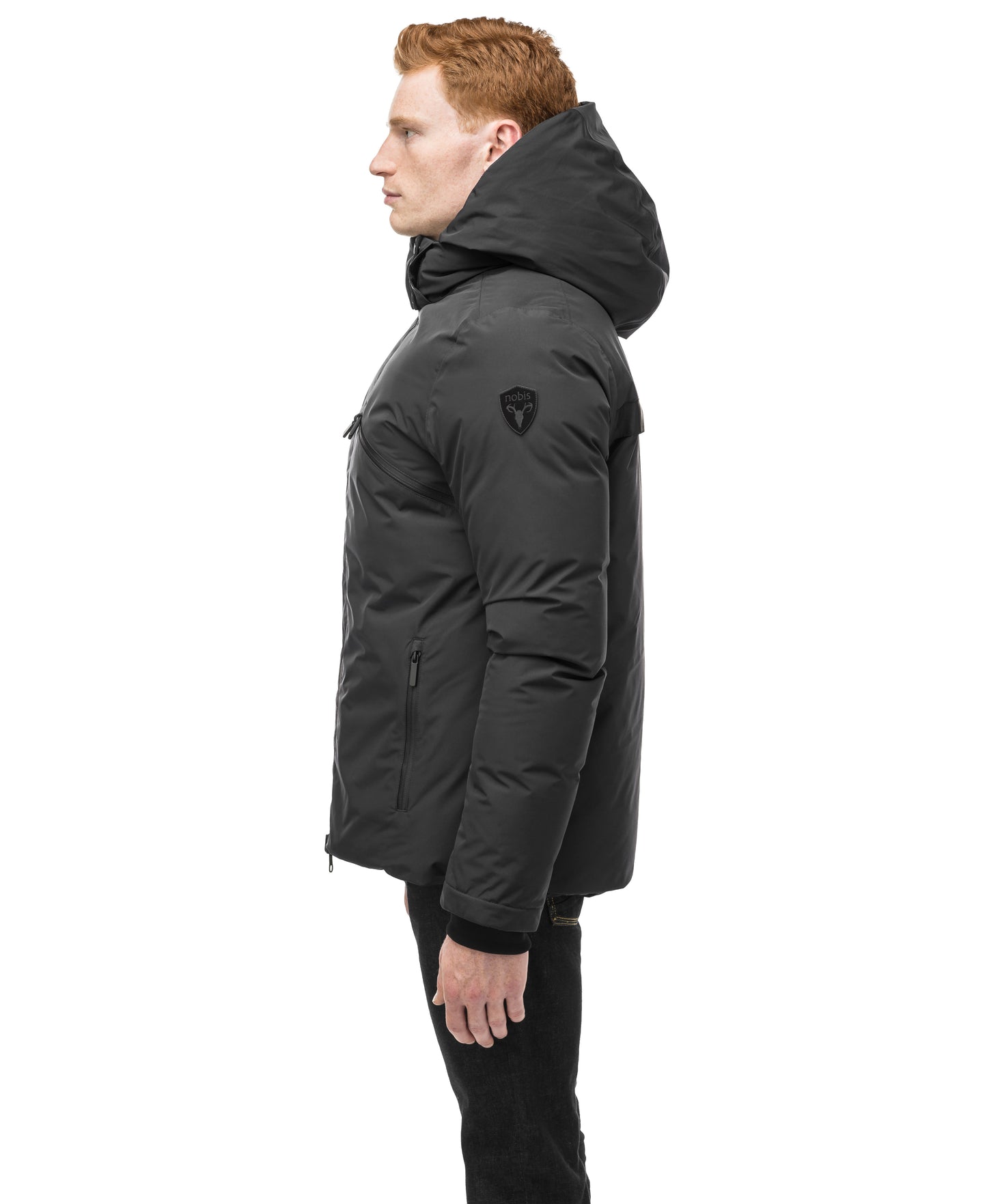 Oliver stands in profile against a white background, wearing the versatile Nobis Oliver Men's Reversible Puffer Jacket with a hood, effortlessly transitioning his look from day to night.