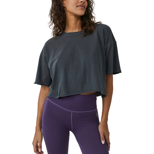 Woman wearing a distressed gray cropped Free People Movement Inspire Tee with an oversized boxy fit and purple leggings, standing against a white background.