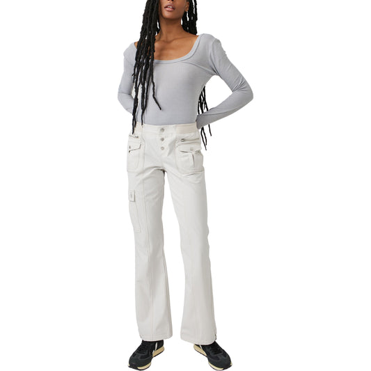 A woman wearing Free People Movement's Cascade Flare in Muted Beige and white relaxed pants with cargo pockets stands facing the camera with a neutral expression.
