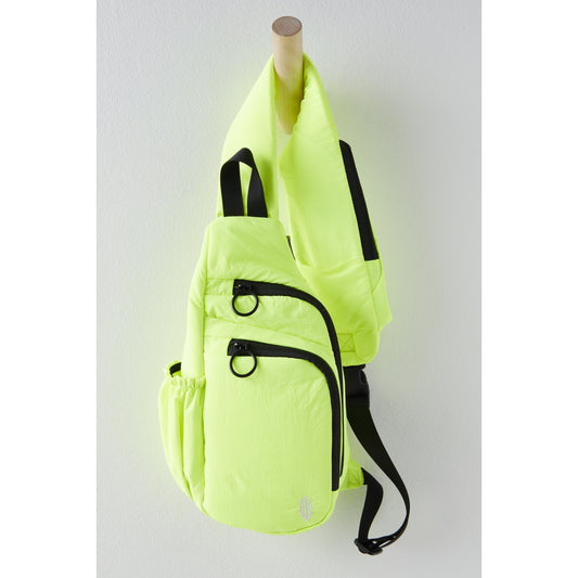 Neon green Renegade Sling bag hanging on a wooden peg against a white wall, featuring black straps and zippers, and a small emblem on the side.