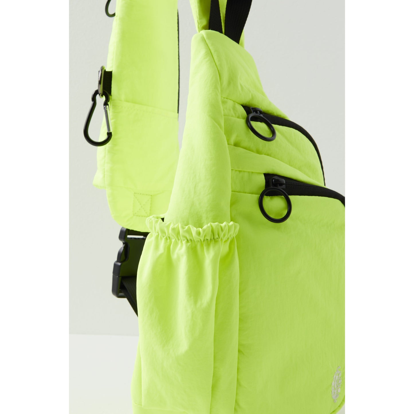 Neon green Renegade Sling with a ruched pocket detail, adjustable black straps, and metallic rings by Free People Movement.