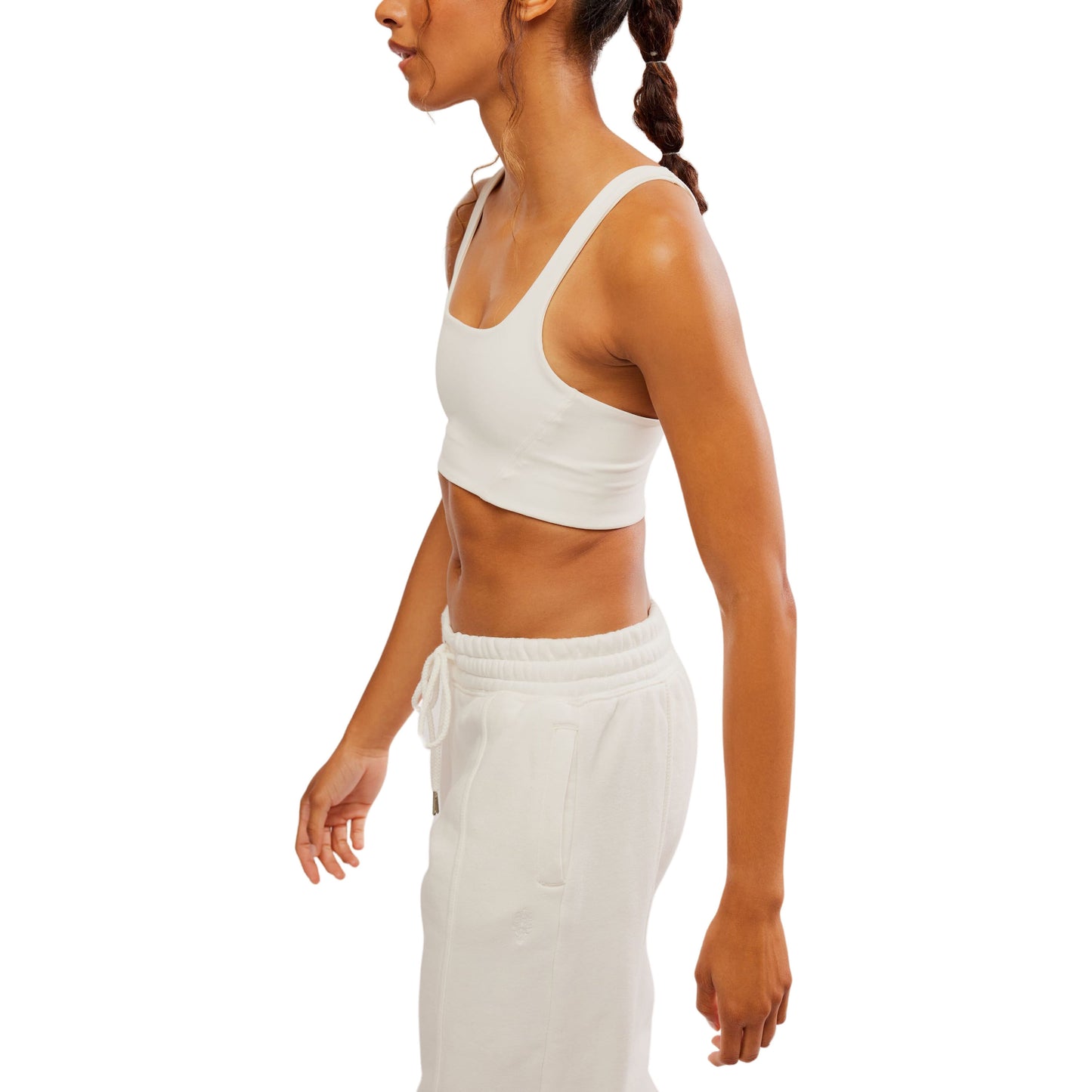 Profile view of a woman wearing a Free People Movement Never Better SQ Neck Bra in White and drawthread pants, isolated on a white background.