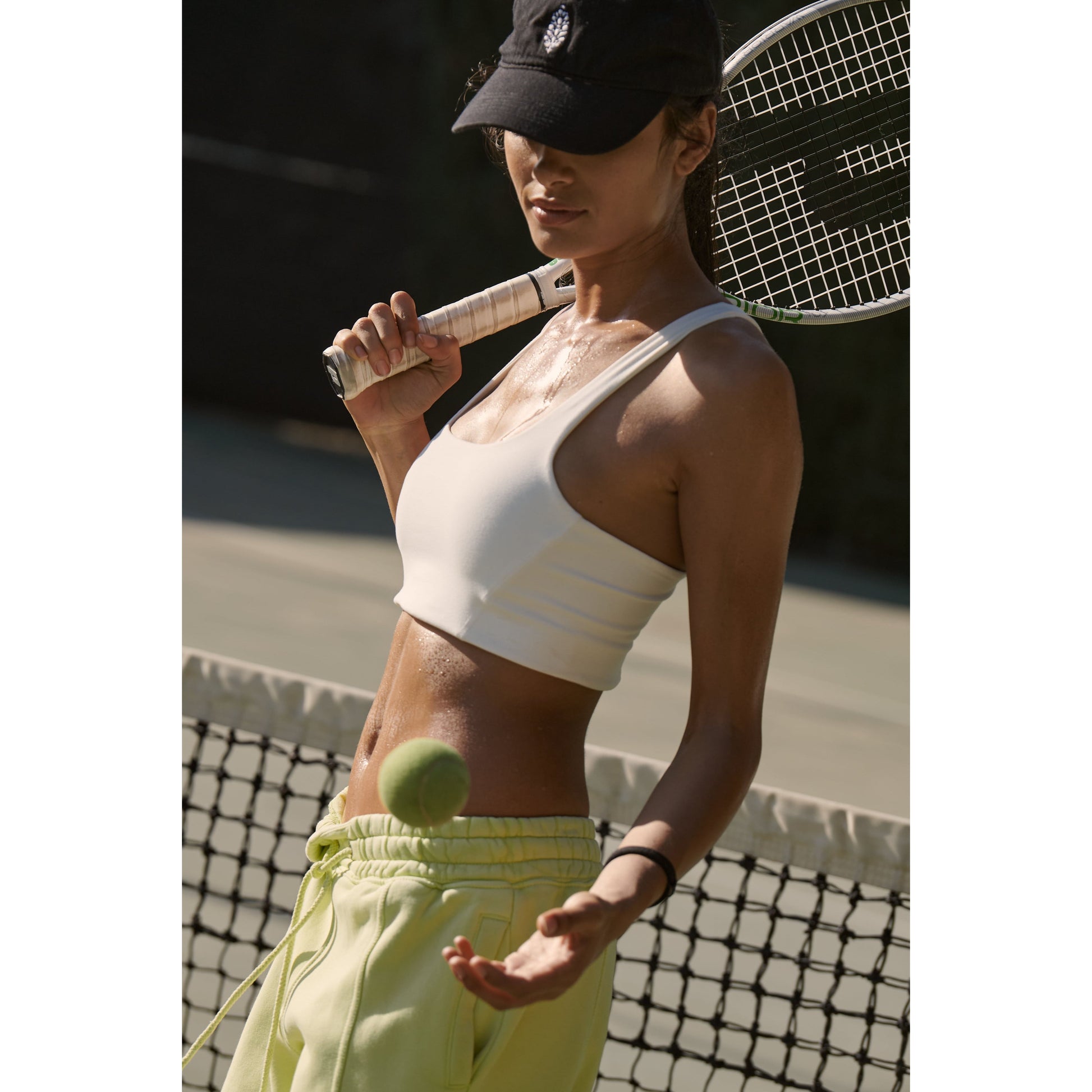 Woman in Free People Movement sportswear with a breathable design balancing a tennis ball on a racket on a sunny court.