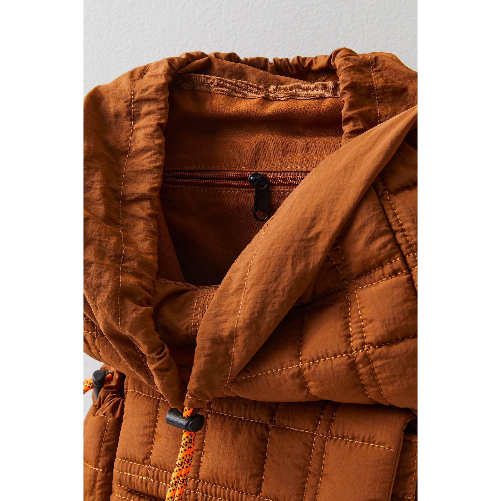 Close-up of an open Free People Movement Summit Backpack in brown with a detailed focus on the zipper and textured stitching.