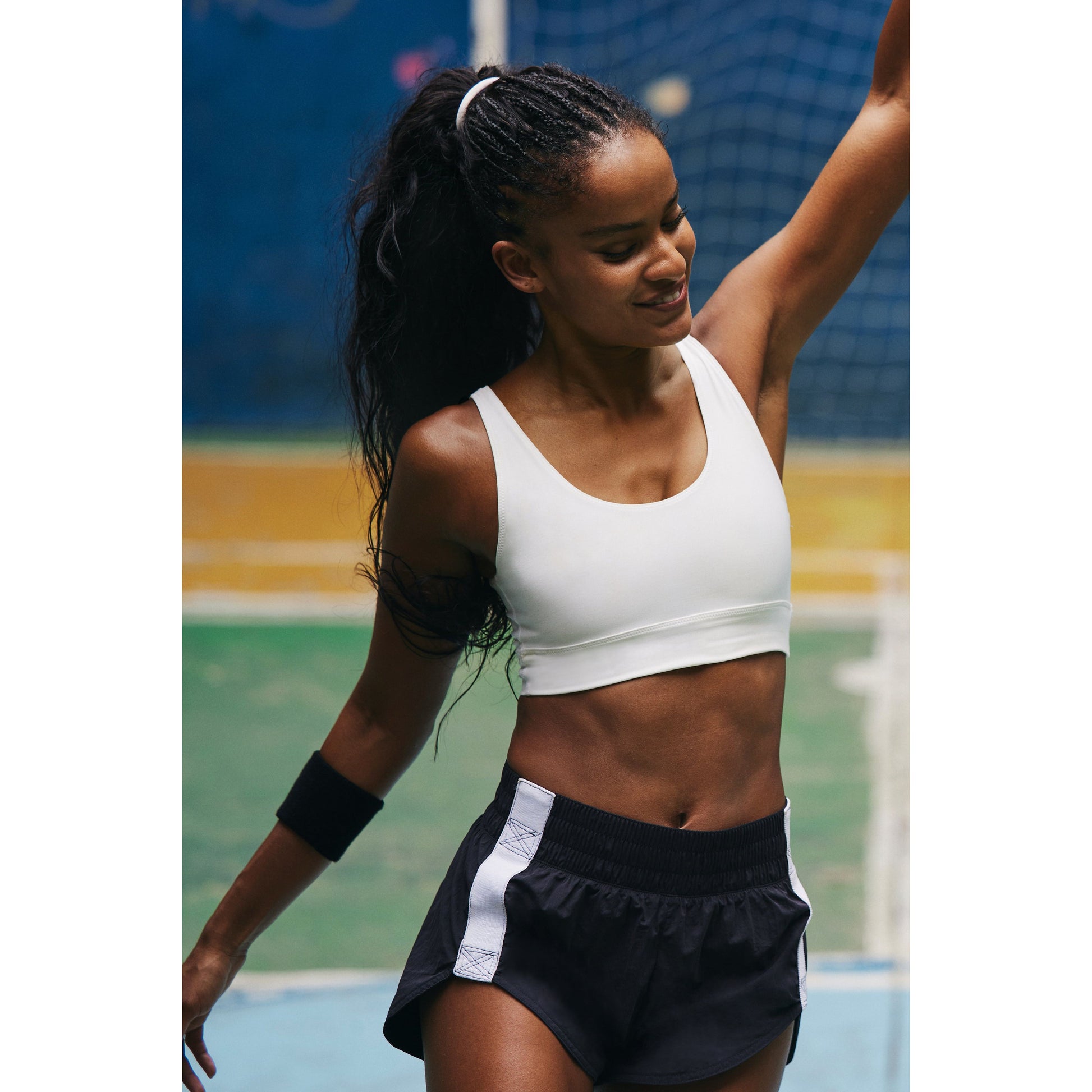 A young woman in Free People Movement's Trail Angel Short, Black Combo dancing joyfully on a basketball court.