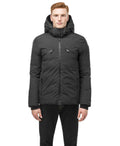 A person wears the Oliver Men's Reversible Puffer Jacket by Nobis, a dark hooded winter coat, facing forward with hands at their sides.