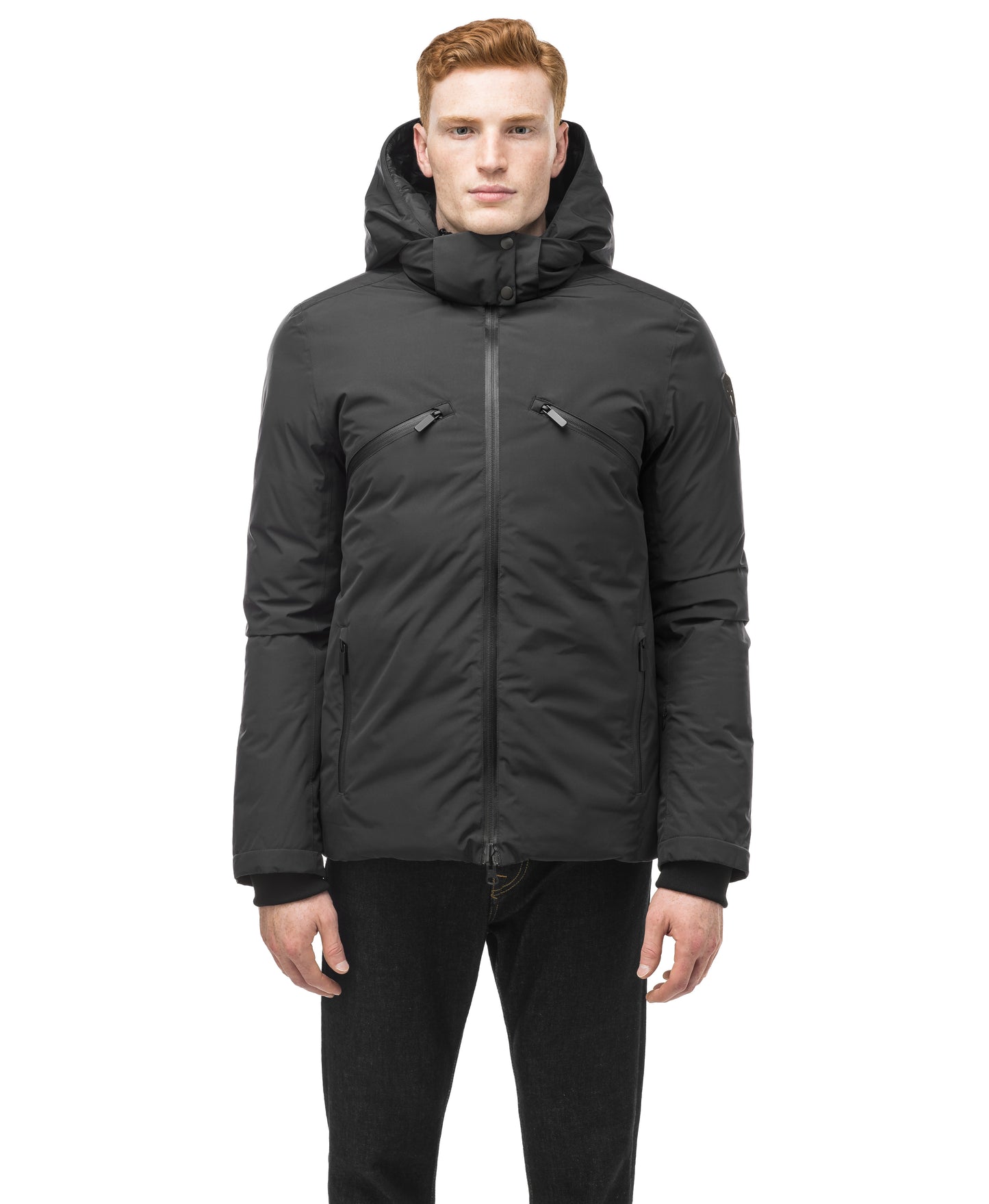 A person wears the Oliver Men's Reversible Puffer Jacket by Nobis, a dark hooded winter coat, facing forward with hands at their sides.