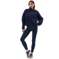 A person in a navy Pieper Fleece from Halfdays, paired with dark leggings and sneakers, stands with one leg slightly bent, looking to the side.