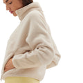 A person is wearing the Pieper Fleece by Halfdays, featuring a beige Sherpa design with a high collar, along with yellow pants, facing left.