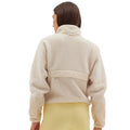 A person dressed in a Pieper Fleece by Halfdays and yellow leggings stands with their back to the camera against a neutral background, highlighting the jacket's performance durability.